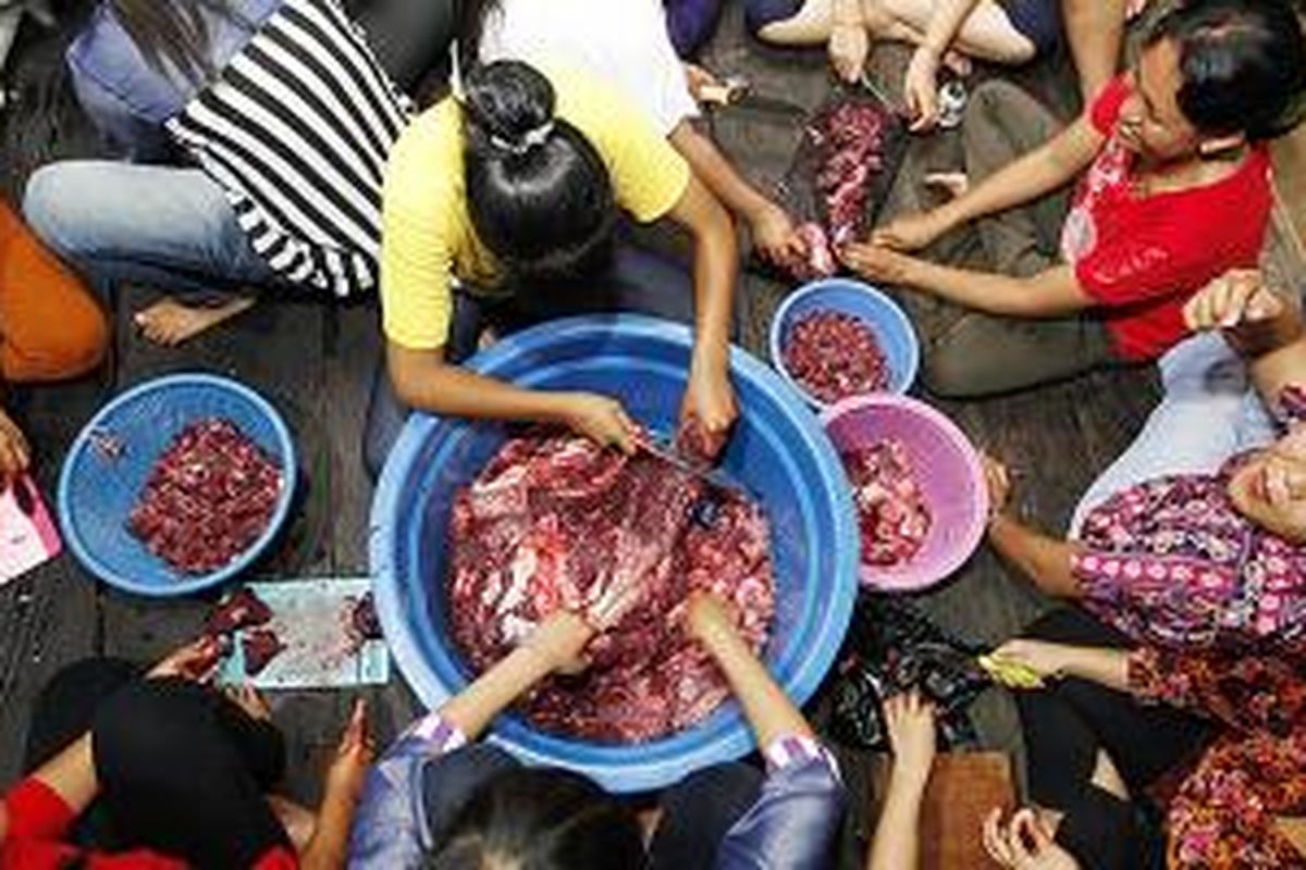 Di dapur, perempuan memotong daging kerbau untuk dimasak dan disajikan dalam makan malam bersama di Taman Budaya Sendawar, Kutai Barat, Kamis (7/11/2013). Masyarakat umum dan enam kelompok etnis, yaitu Benoaq, Bahau, Aoheng, Kenyah, Tunjung, dan Melayu, menyantap bersama hidangan itu.