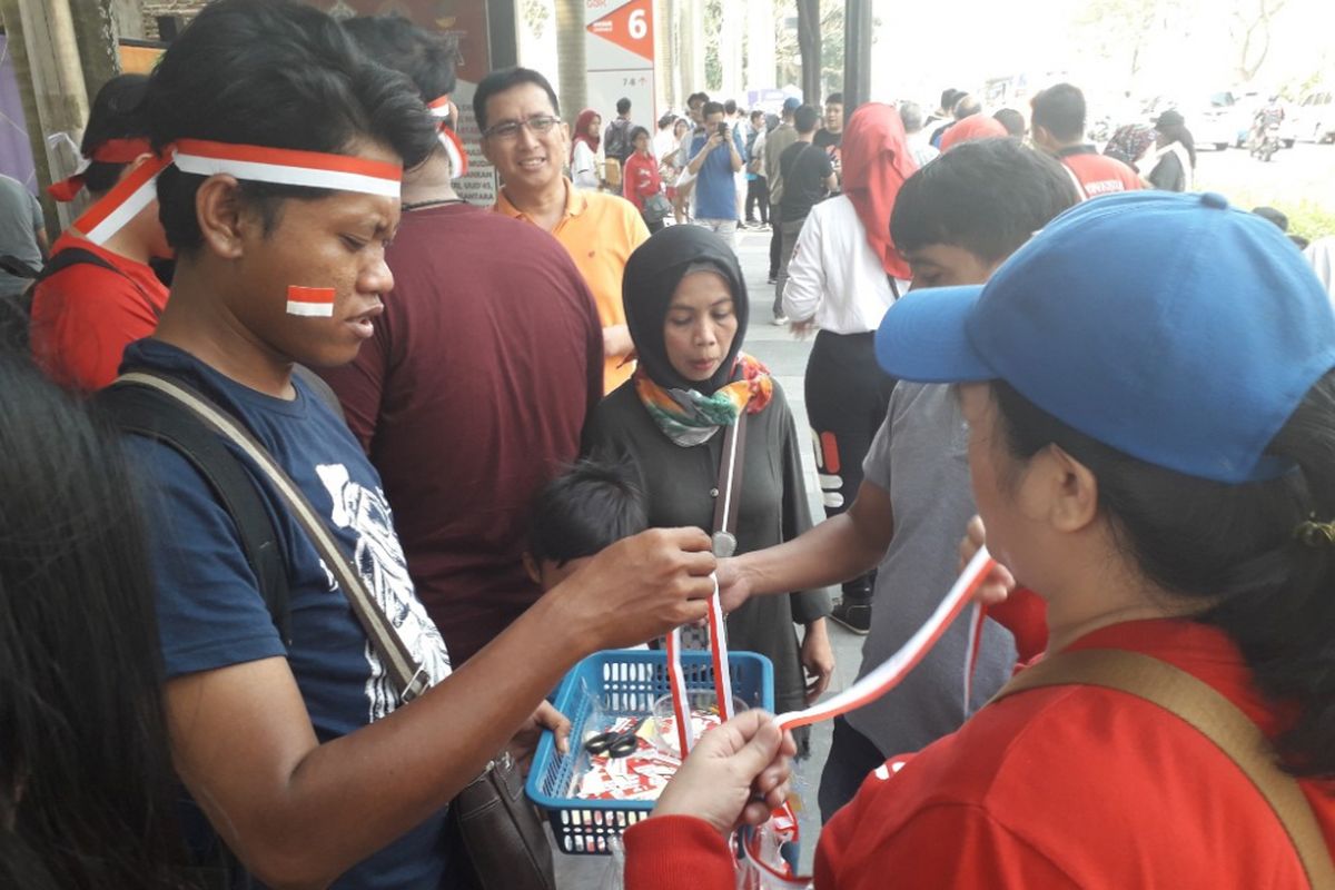 Iwan, pedagang stiker dan ikat kepala, tengah melayani sejumlah pembeli di Jalan Jenderal Sudirman dekat Pintu 7 GBK, Sabtu (18/8/2018).