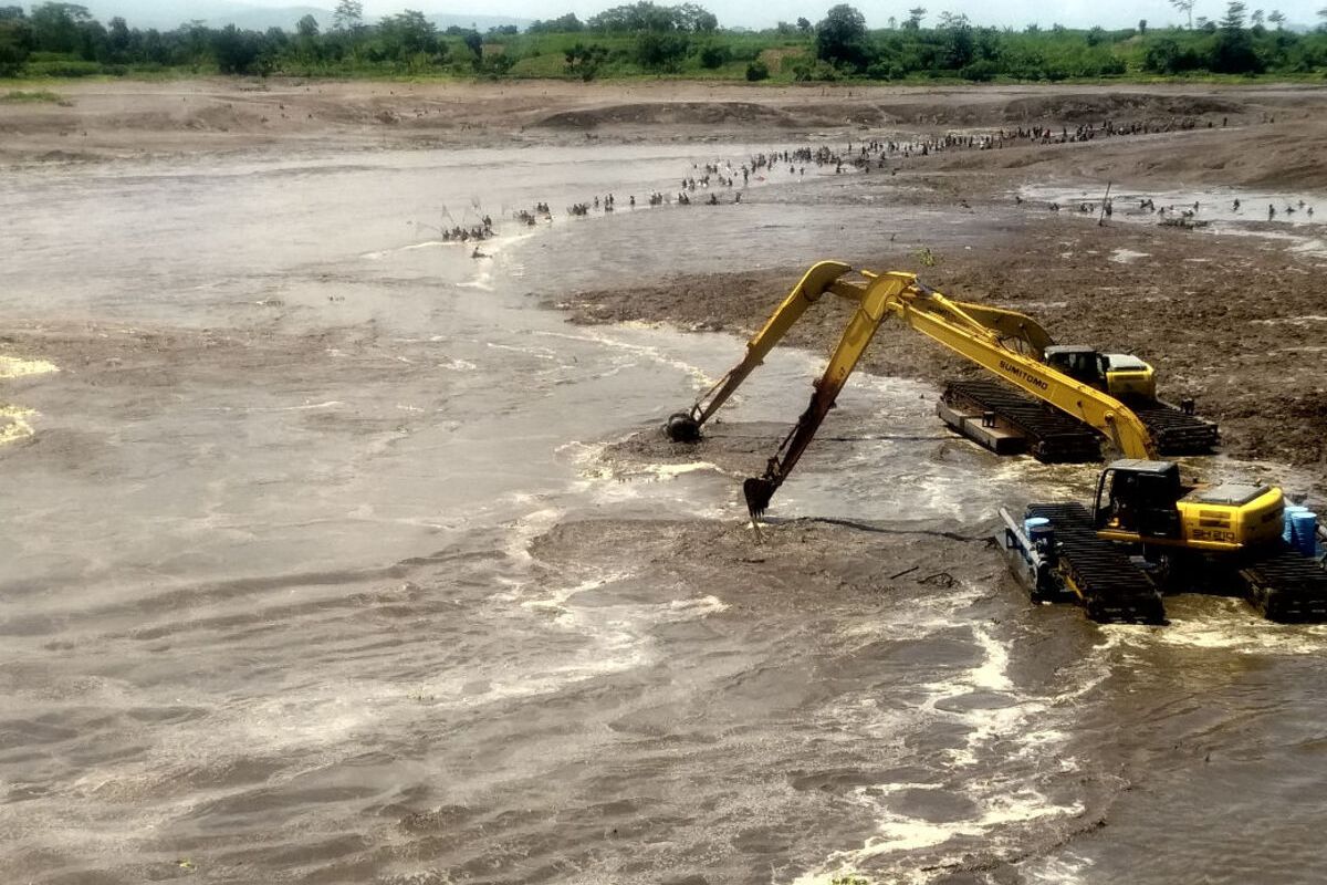 Caption 1: Air mengalir deras dari salah satu pintu air Bendungan Wlingi di Kabupaten Blitar selama proses flushing yang dimulai Minggu (27/4/2025). Caption 2: Dua ekskavator mengeruk gundukan sedimen di waduk Bendungan Wlingi di Kabupaten Blitar selama berlangsungnya kegiatan flushing, Minggu (27/4/2025)