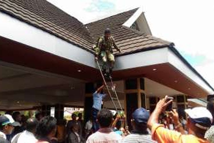 Sejumlah petugas TNI AU tampak berusaha menurukan seorang penerjun yang terjatuh di atas atap tribun lapangan merdeka Ambon, Rabu (7/9/2016).  