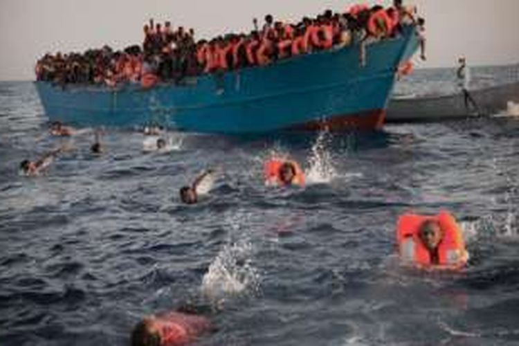 Sebagian dari 6.500 migran yang berhasil diselamatkan dengan menggunakan pelampung berenang menuju kapal penyelamat dari petugas jaga pantai Italia, Senin (29/8/2016) di Laut Mediterania.