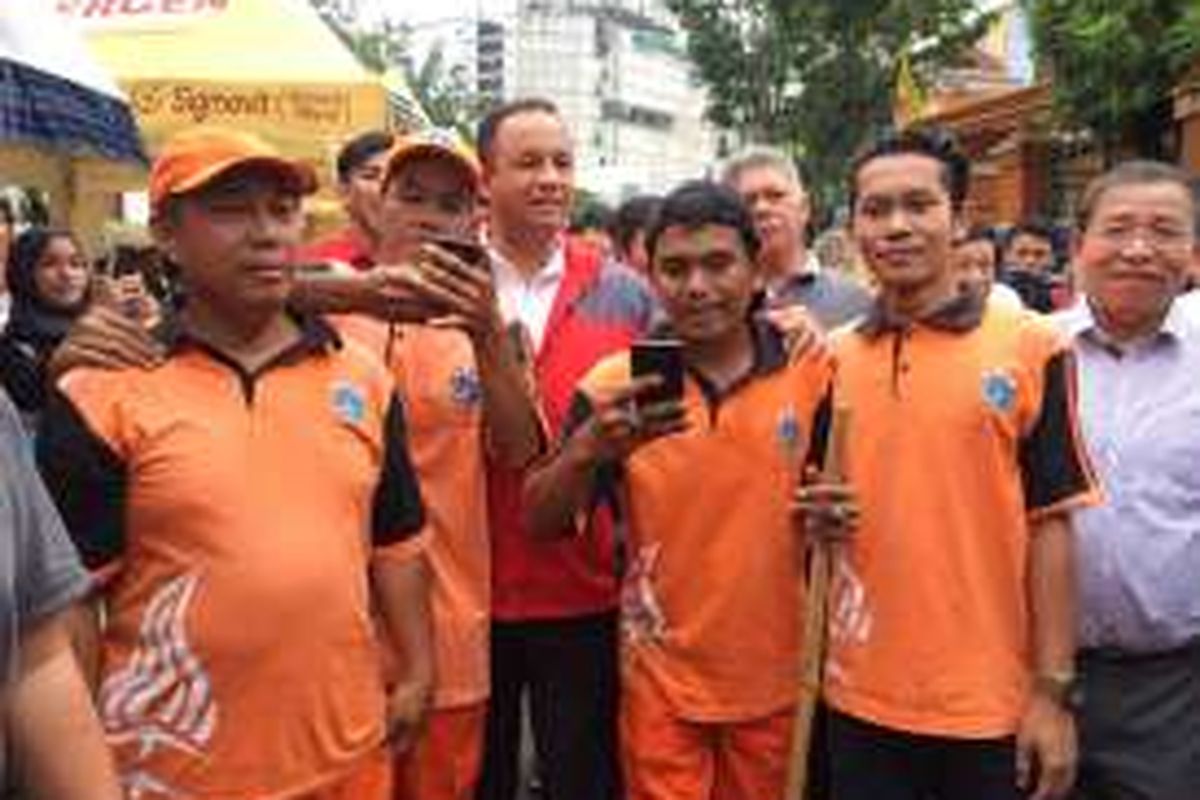 Bakal calon gubernur DKI Jakarta, Anies Baswedan, tiba-tiba dihampiri sejumlah pekerja Penanganan Prasarana dan Sarana Umum (PPSU) Kelurahan Glodok, Jakarta Barat, Minggu (23/10/2016). Para pekerja PPSU langsung berebut untuk meminta berfoto.