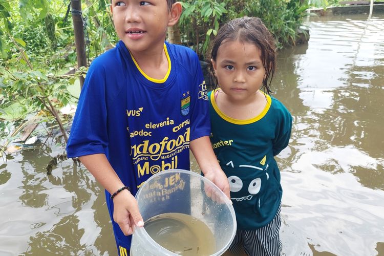 Azril (kiri) dan Salwa (kanan) saat mencari ikan di RT04/RW08, Jurumudi, Kecamatan Benda, Kota Tangerang, pada Jumat (21/1/2022), saat banjir terjadi.