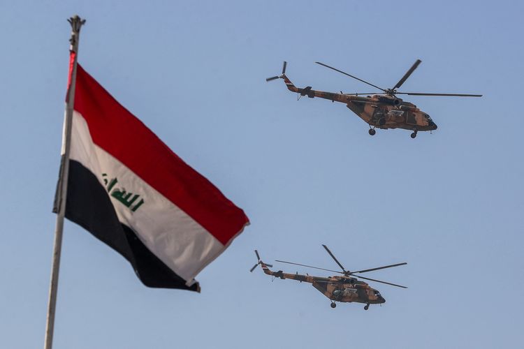Helikopter Angkatan Udara Irak terbang saat perayaan Hari Angkatan Bersenjata, bersamaan dengan bendera Irak yang berkibar di Baghdad, 6 Januari 2025.
