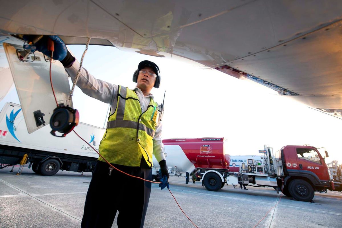 Ilustrasi pekerja sedang mengisi bahan bakar untuk pesawat.