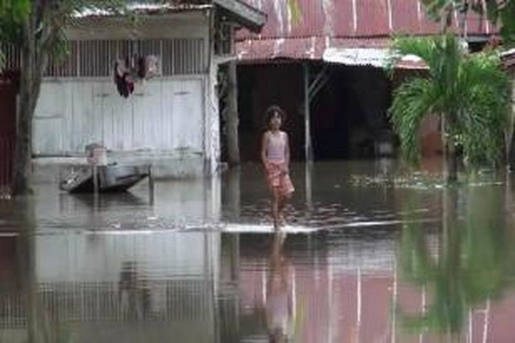Seorang anak melintasi banjir di halaman rumahnya. Sedikitnya 70 rumah di kawasan dusun Labui, Gampong (desa) Ateuk Pahlawan, Banda Aceh direndam banjir akibat luapan anak sungai Krueng Aceh, Selasa (23/12/2014). Dalam sebulan terakhir sudah 3 kali dusun ini dilanda banjir akibat intensitas hujan yang tinggi.