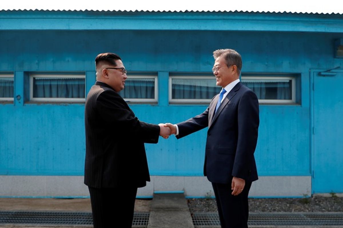Pemimpin Korea Utara Kim Jong Un (kiri) berjabat tangan dengan Presiden Korea Selatan Moon Jae-in saat bertemu di Garis Demarkasi Militer, di desa perbatasan Panmunjom, Jumat (27/4/2018).
