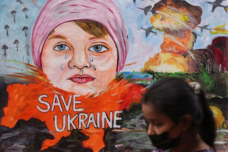 Seorang gadis berjalan melewati lukisan yang menggambarkan krisis antara Rusia dan Ukraina, di luar sebuah sekolah seni di Mumbai, India, Kamis (24/2/2022). 