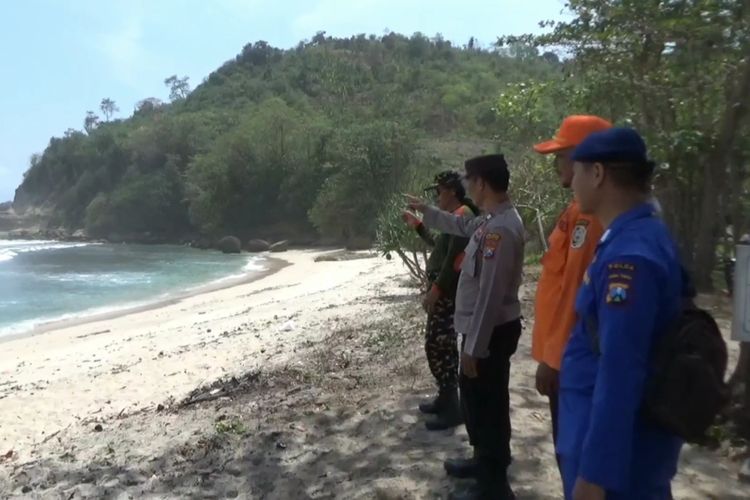 Petugas menunjukkan tebing tempat korban hilang tersapu ombak di Pantai Sanggar Kecamatan Tanggunggunung Kabupaten Tulungagung Jawa Timur, Senin (13/10/2023).