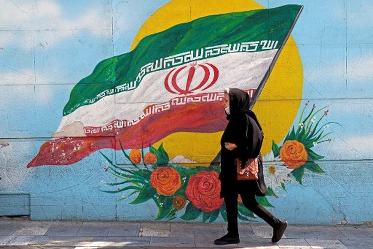 Dalam file foto yang diambil pada 11 Oktober 2022 ini, seorang wanita berjalan melewati mural di ibu kota Iran, Teheran.