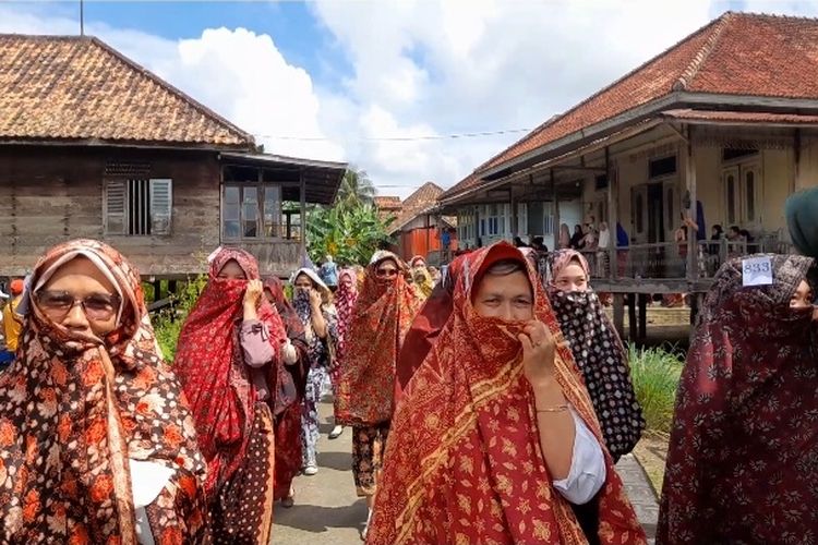 Para perempuan menggunakan Tudung Lingkup sebuah tradisi berusia ratusan tahun di kota santri Seberang Kota Jambi, Minggu (28/8/2022).