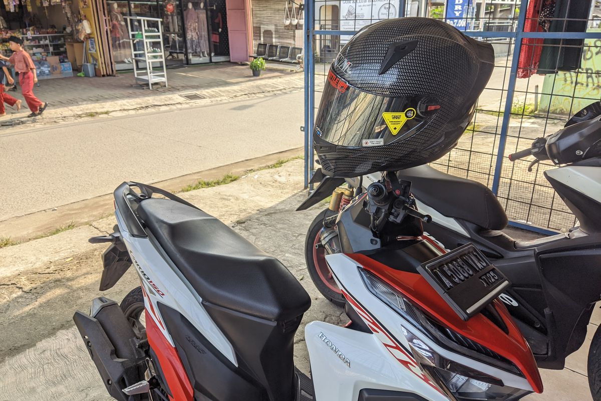 Ilustrasi Helm digantung di Spion Motor