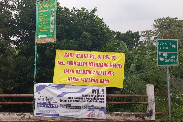 Penampakan banner penolakan atas aktivitas bank keliling terpasang di lingkungan RT 01 RW 01, Sukmajaya, Depok.