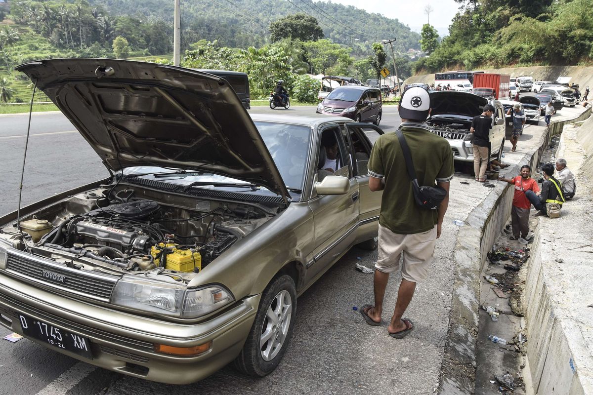 Sejumlah kendaraan pemudik yang mengalami kerusakan parkir di bahu Jalan Lingkar Gentong Bawah, Kadipaten, Kabupaten Tasikmalaya, Jawa Barat, Jumat (6/5/2022). Puluhan kendaraan pemudik mengalami mogok atau kerusakan akibat tidak kuat menanjak sehingga arus lalu lintas di Jalur Selatan tersendat.