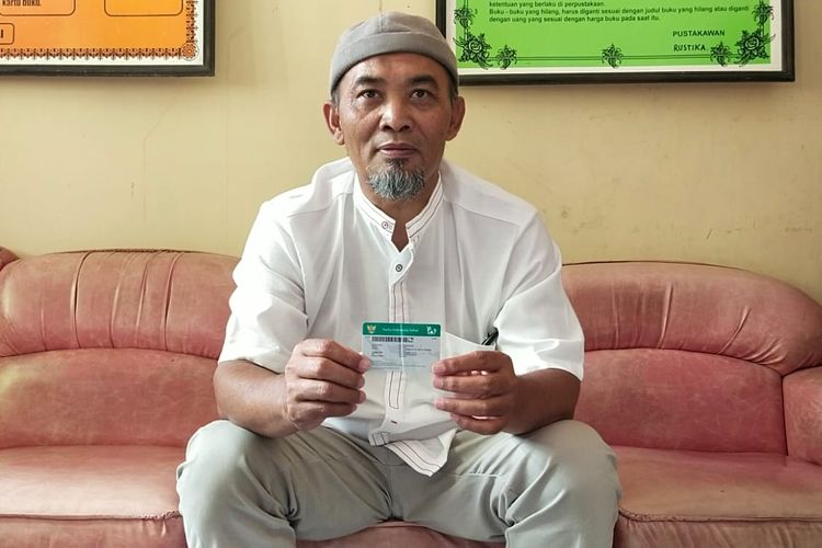 Kepala Desa Wunut, Iwan Sulistyo Setiawan, berfoto di ruang kerjanya di Desa Wunut, Kecamatan Tulung, Klaten, Jateng dengan menunjukkan Kartu Indoensia Sehat (KIS), Jumat (12/8/2022). Dia berkomitmen ingin menjadikan semua warganya terdaftar JKN.