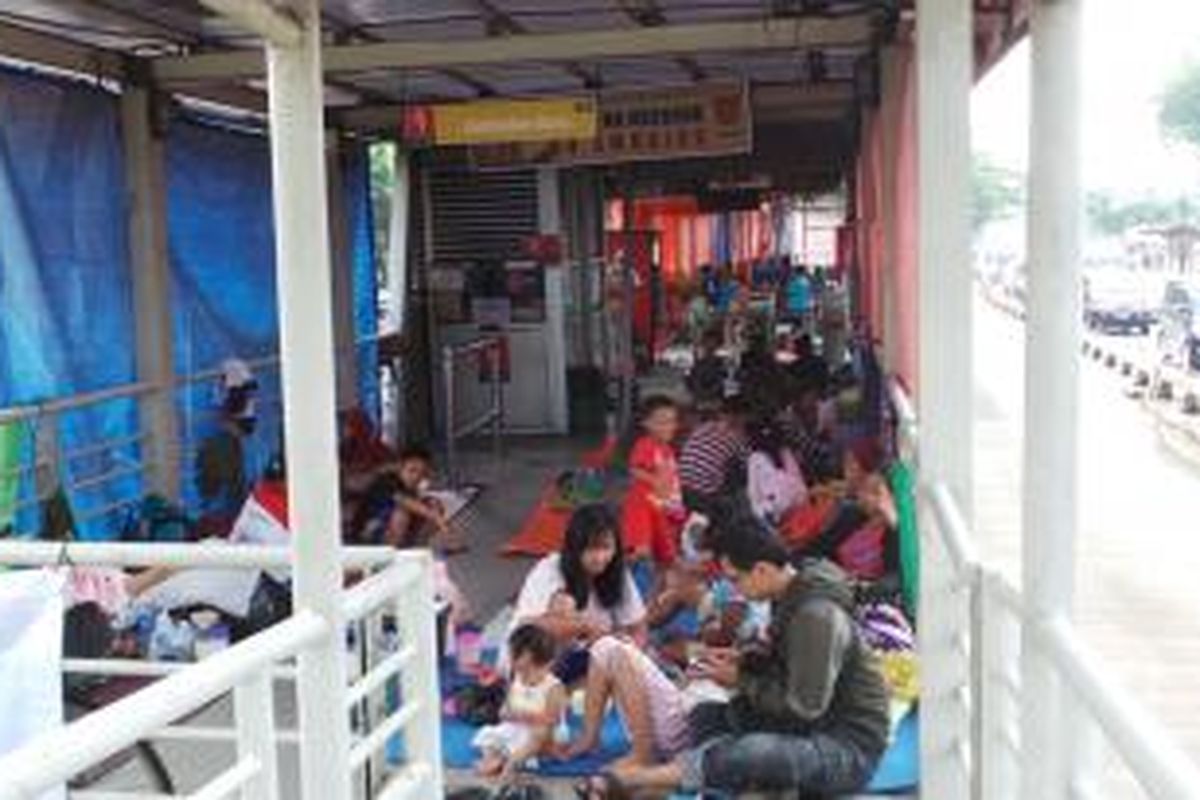 Pengungsi banjir warga Rawabuaya memilih halte transjakarta Jembatan Baru aebagai lokasi pengungsian mereka dari ancaman banjir, Selasa (4/2/2014).
