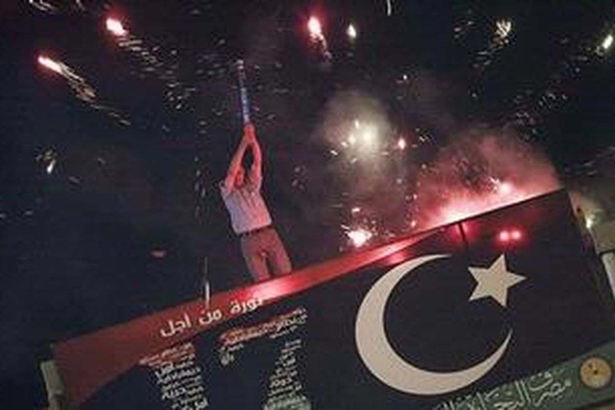 Seorang pria di atap bangunan di Benghazi, Libya timur, Minggu (21/8/2011), menembakkan kembang api ke udara untuk merayakan masuknya pasukan pemerontak ke Tripoli, ibukota Libya.