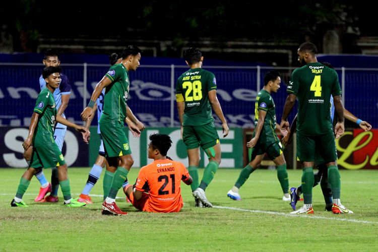 Kiper Persebaya Surabaya Ernando Ary terjatuh seusai menghalau serangan Persela Lamongan pada pêrtandíngan pekan 24 Liga 1 2021-2022 yang berakhir dengan skor 2-2 di Stadion I Gusti Ngurah Rai Denpasar, Kamis (10/2/2022) malam.