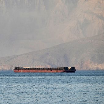 Kapal-kapal melintasi Selat Hormuz pada 24 Juni 2025, saat difoto dari pesisir Khasab, Semenanjung Musandam, Oman.