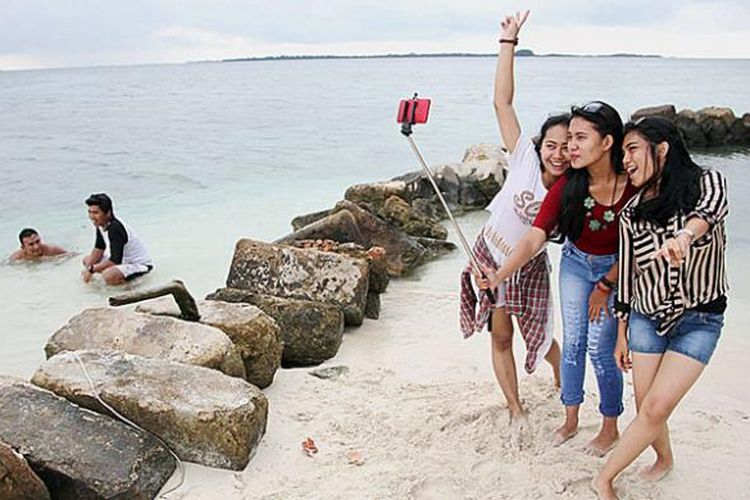 Wisatawan berfoto selfie di Pulau Genteng Kecil, Kelurahan Pulau Harapan, Kecamatan Kepulauan Seribu Utara, Kepulauan Seribu, Minggu (25/1/2015). Hamparan pasir putih di pantai pulau-pulau kecil di kepulauan seribu menjadi daya tarik wisata.