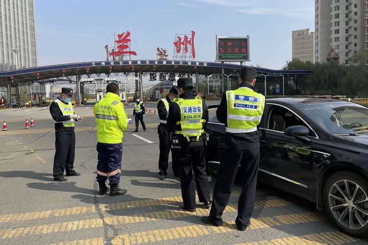 Polisi berjaga di checkpoint untuk melihat hasil tes Covid-19 yang harus ditunjukkan warga saat masuk dan keluar kota Lanzhou, provinsi Gansu, China, pada 26 Oktober 2021.