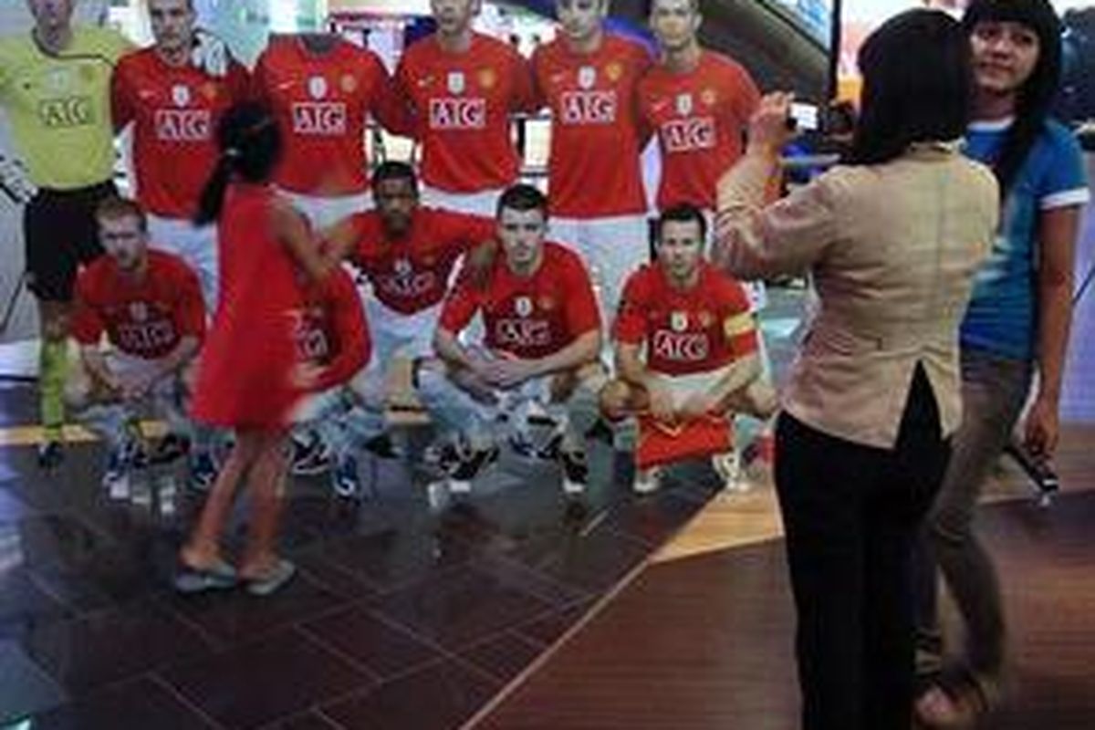 Pengunjung berpose dengan poster pemain Manchester United di stan Tri di FX Plaza, Senayan, Jakarta.
