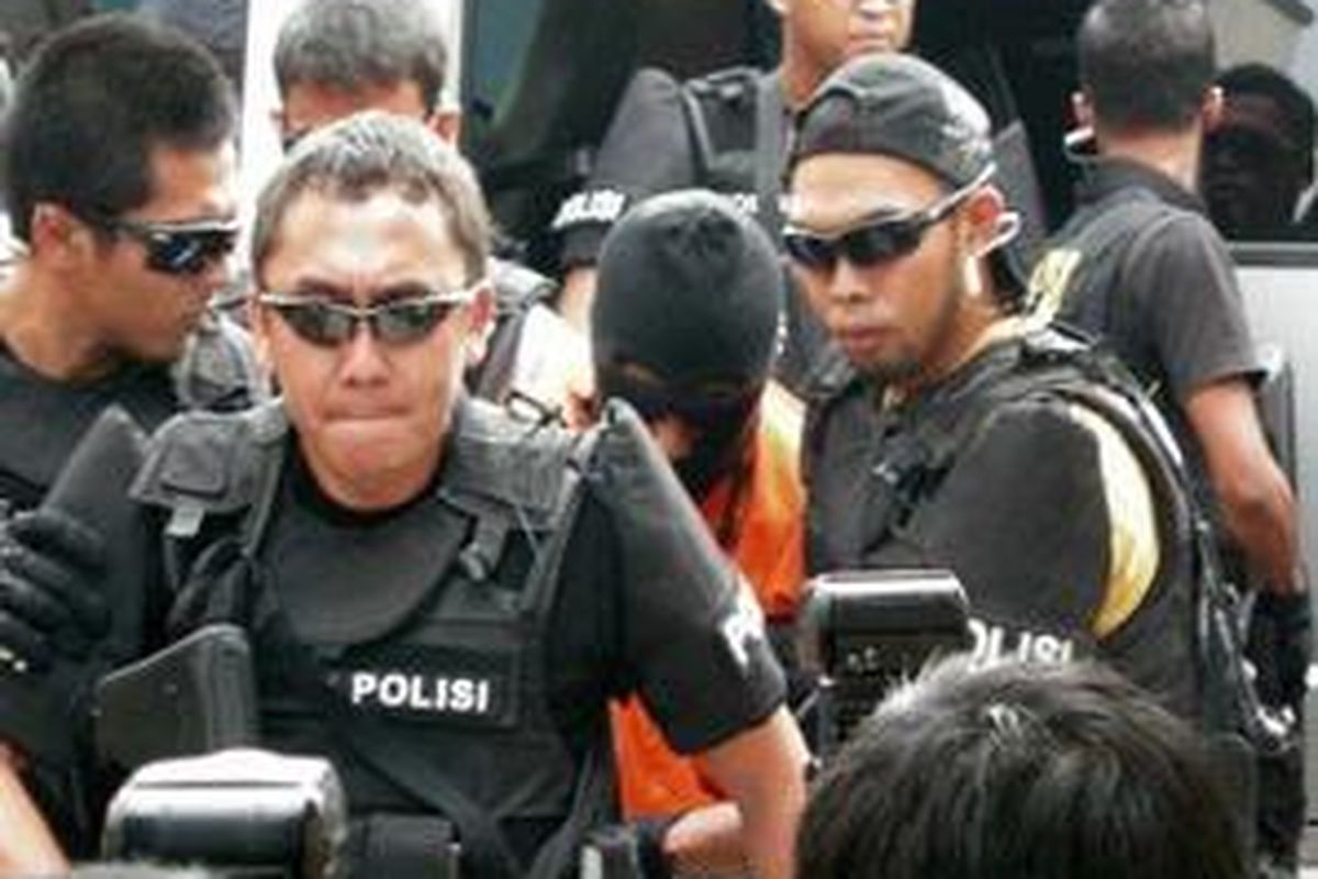 Polisi mengawal dua tersangka teroris yang tertangkap di daerah Temanggung, Jawa Tengah saat dipindahkan ke Markas Komando Brimob, Kelapa Dua, Depok, Senin (10/8). Kedua teroris tersebut diduga merupakan anak buah Noordin M Top. 