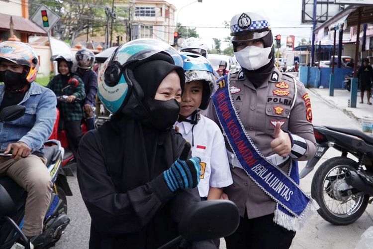 Seorang Polwan dari Polres Gorontalo Kota membagikan helm kepada pengendara motor pada Operasi Zebra Otanaha.