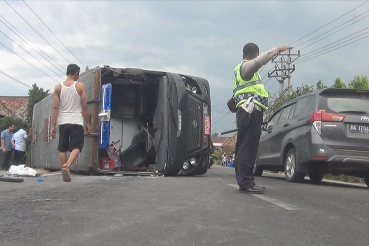 Polisi dari Satuan Lalu Lintas Ogan Ilir mengatur lalu lintas di TKP kecelakaan untuk mengurai kemacetan. Di belakang terlihat kendaraan tahanan yang terguling di tengah jalan usai terbalik saat menghindari tabrakan dengan kendaraan boks