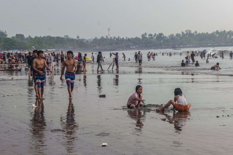 Dua anak bermain pasir di Pantai Anyer, Kabupaten Serang, Banten, Minggu (23/4/2023). Objek wisata pantai yang menjadi salah satu destinasi wisata warga Banten dan Jakarta tersebut ramai dikunjungi wisatawan pada hari kedua Lebaran 1444 H.