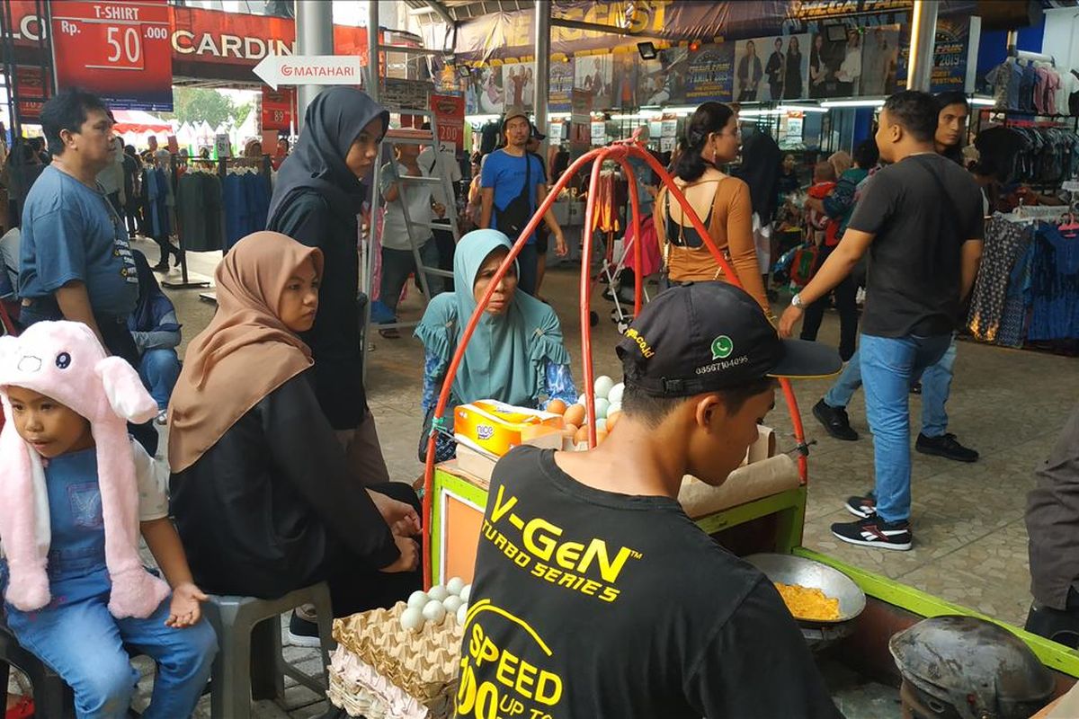 Pedagang kerak telor di Pekan Raya Jakarta tampak sibuk menyelesaikan pesanan pembeli.