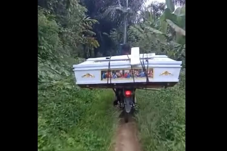 Seorang pemotor membawa peti dan salib di Dusun Bulu Malanda, Nagori Parmonangan, Kecamatan Dolok Panribuan, Kabupaten Simalungun.
