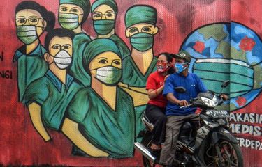 Pengendara motor melintas di depan mural tentang pandemi virus corona atau COVID-19 di Jalan Raya Jakarta-Bogor, Depok, Jawa Barat, Jumar (3/4/2020). Mural tersebut ditujukan sebagai bentuk dukungan kepada tenaga medis yang menjadi garda terdepan dalam menghadapi COVID-19 di Indonesia. 