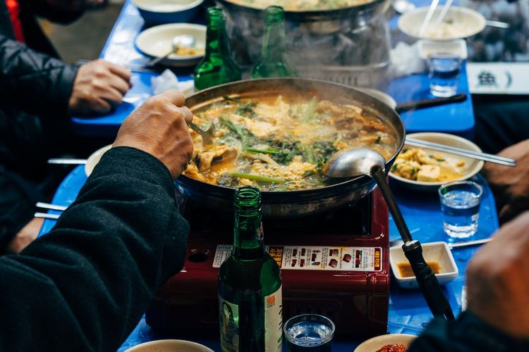 Ilustrasi masakan Korea dimasak di atas kompor portabel. 