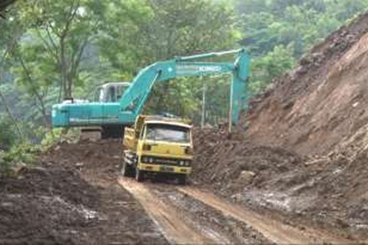 Alat berat membersihkan material longsor yang menutup jalan di Kilometer 16,desa Nglinggis kecamatan Tugu Kabupaten Trenggalek.