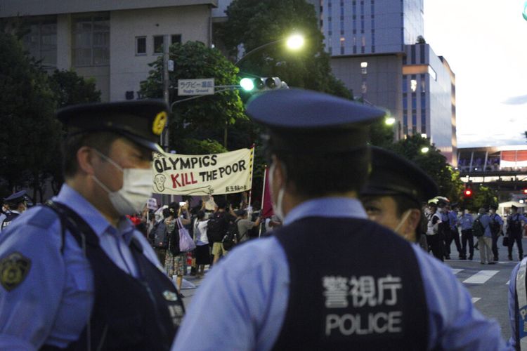 Petugas polisi berkumpul saat pengunjuk rasa anti-Olimpiade menggelar unjuk rasa di depan Stadion Nasional di mana upacara penutupan Olimpiade Tokyo akan dimulai di Tokyo, Jepang, Minggu, 8 Agustus 2021. 