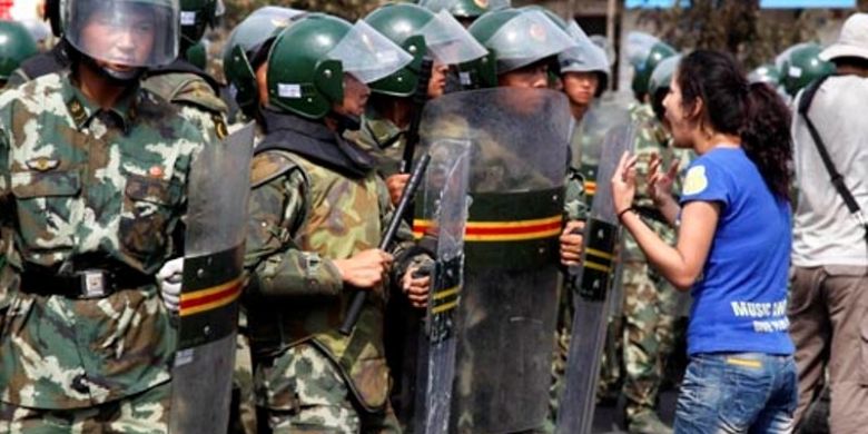 Seorang perempuan Uighur berteriak di depan pasukan paramiliter China di ibu kota wilayah otonomi Uighur, Urumqi pada Juli 2009. Aksi unjuk rasa dan kekerasan kerap terjadi di Xinjiang karena warga Uighur merasa disisihkan oleh etnis Han yang adalah pendatang.

