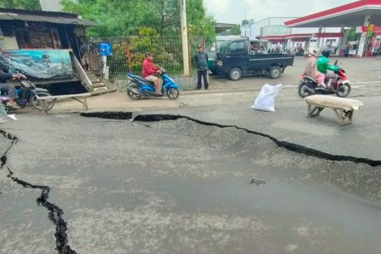 Pengendara motor melintasi jalan yang amblas di Jalan Cibolerang, Kota Bandung, Jawa Barat, Jumat (2/12/2022).  