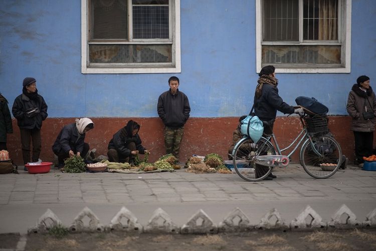 Foto ini diambi pada 30 November 2016 menunjukkan orang-orang menjual buah dan sayur di jalan Kaesong, Korea Utara. (AFP/Ed Jones)