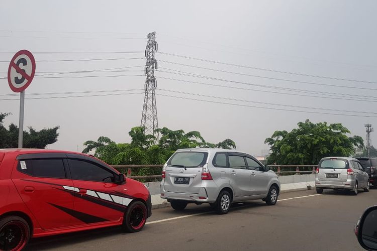 Pengemudi menunggu berakhirnya ganjil genap di bahu jalan tol.