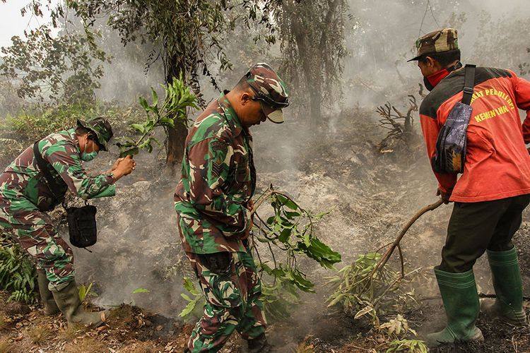 Prajurit TNI dari Kodim 0301 Kota Pekanbaru dibantu Masyarakat Peduli Api (MPA) berusaha menghalau api yang membakar semak belukar dengan alat seadanya saat menunggu bantuan petugas Pemadam datang ke lokasi lahan gambut yang terbakar di Pekanbaru, Riau, Kamis (12/9/2019). Tidak adanya sumber air di lokasi lahan yang terbakar membuat petugas kewalahan untuk melakukan pemadaman di lokasi tersebut.