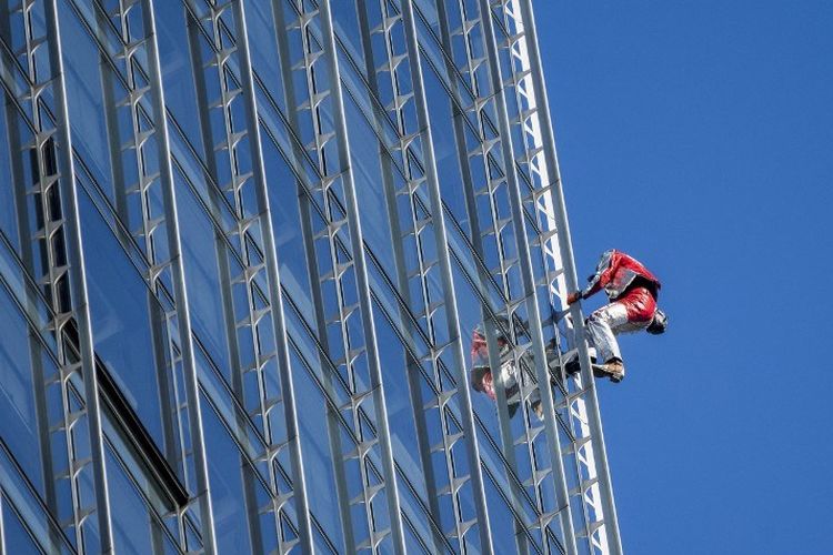 Pendaki perkotaan Prancis Alain Robert, yang dikenal sebagai Spiderman Prancis, memanjat gedung Skyper setinggi 153,8 m di Frankfurt am Main, Jerman barat pada 23 November 2021.