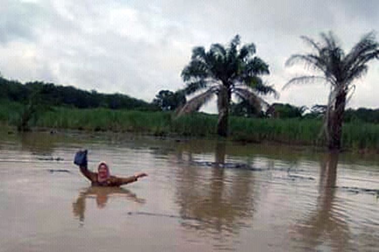 Yuliana, guru SDN 3 Bandar Agung, Lampung Utara nekat menerjang banjir setinggi dada untuk pergi mengajar. (Foto: tugiadr/facebook)