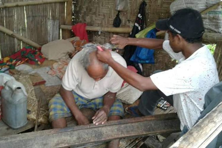 Seorang relawan KKI Peduli Orang Dengan Gangguan Jiwa (ODGJ) Kab. Manggarai Barat, Kristo Gerry (35) sedang memangkas rambut penderita gangguan jiwa di salah satu pondok di kampung pedalaman, Kecamatan Welak, Jumat, (13/9/2019).