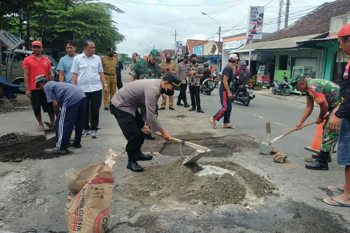 Unsur Muspika Kecamatan Nglegok, Kabupaten Blitar bergotong royong menambal jalan berlubang yang menjadi penyebab tewasnya seorang pengendara sepeda motor, Selasa (25/10/2022)