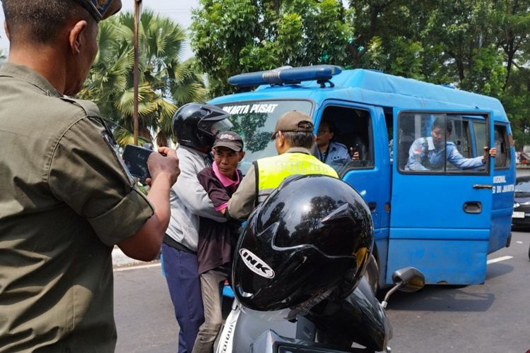 Petugas menangkap seorang juru parkir (liar) yang sedang beroperasi di kawasan Pasar Senen Blok III, Senen, Jakarta Pusat, Rabu (5/7/2023).