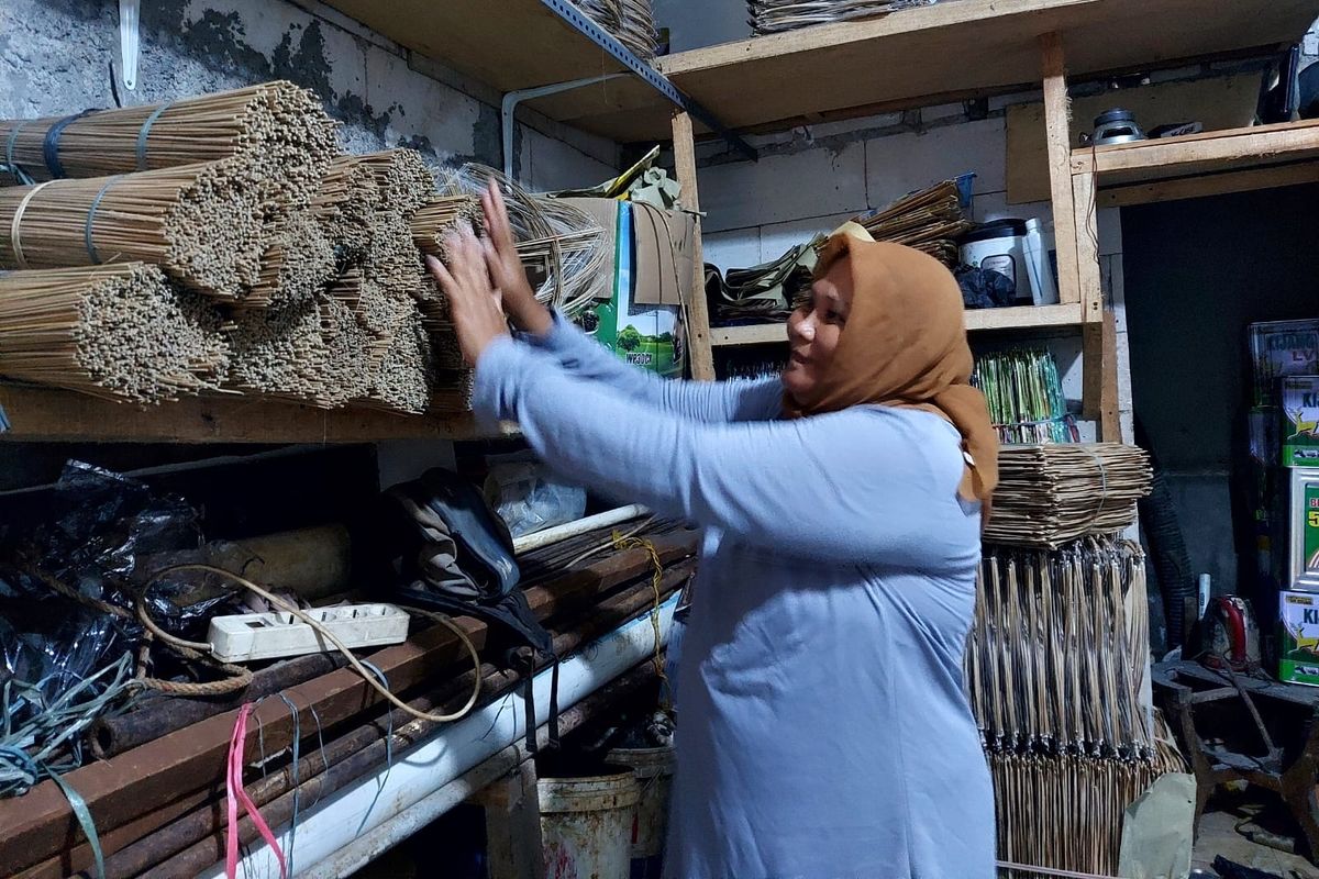 Tinawati atau Titin (37) tengah menata bahan baku layang-layang. Bahan baku ini nantinya diberikan ke perajin untuk kemudian dibuat layang-layang