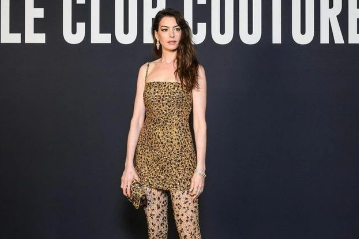 Anne Hathaway menghadiri Paris Fashion Week dengan minidress bermotif macan tutul lengkap dengan legging dan tas tangan yang sama.