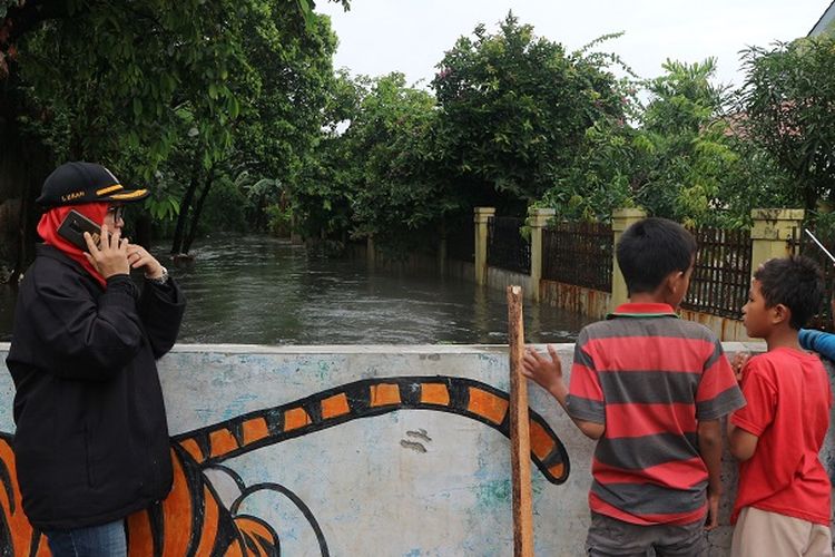 Lurah Sukabumi Selatan, Mayanti tengah menelpon saat memantau banjir di wilayahnya pinggir Kali Sekretaris Kebon Jeruk, Jakarta Barat, Rabu (1/1/2020) siang.