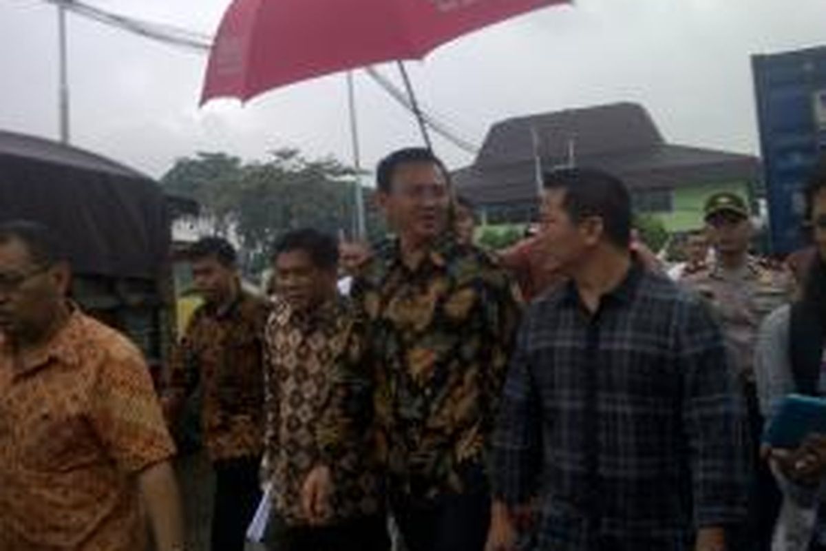 Gubernur DKI Jakarta Basuki Tjahaja Purnama dipayungi saat blusukan ke Pasar Induk Beras Cipinang, Jakarta Timur, Jumat (23/1/2015). 